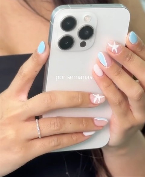 Uñas celestes terminadas sosteniendo un teléfono